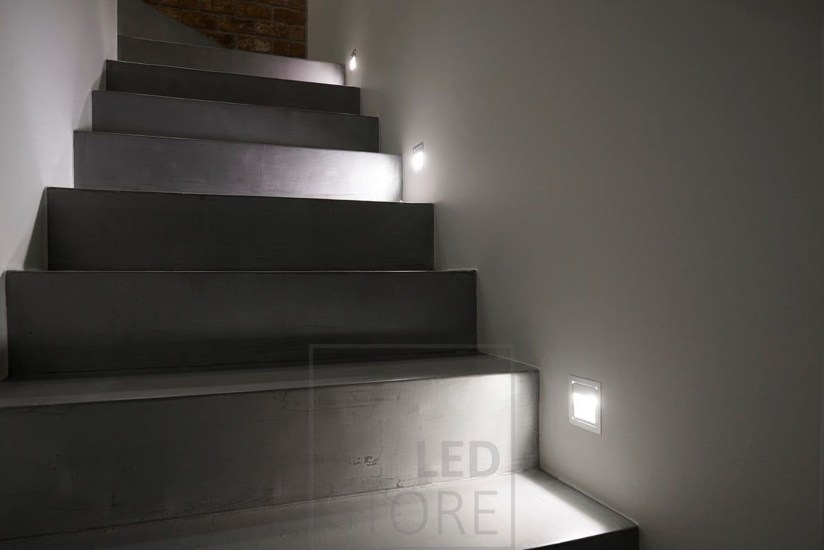 At every third step, a wall-mounted light fixture. The light is soft and illuminates the steps.